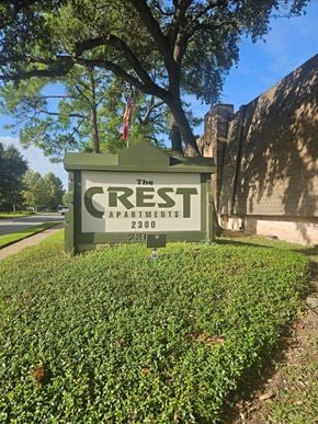 Houston apartment for rent - A sign for The Crest Apartments stands in front of a building.