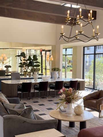 Louisville apartment for rent - A modern living room with a large grey sofa, a round table with a vase of flowers on it, and a chandelier hanging from the ceiling.