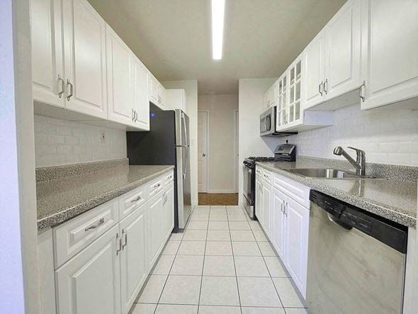 Passaic apartment for rent - a white kitchen with white cabinets and a black refrigerator