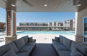 Kansas City townhouse for rent - A large outdoor seating area with a pool and apartment buildings in the background at Woodstone at Metro North Crossing Apartments, Missouri