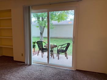 A patio with a table and chairs is visible through a sliding glass door.