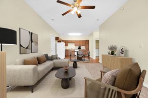 Silvis apartment for rent - A living room with a beige couch, a brown chair, and a ceiling fan. at Deer Valley Apartments, Illinois