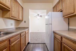 Davenport apartment for rent - A kitchen with wooden cabinets and a white refrigerator. at Kimberly Club Apartments, Iowa, 52807