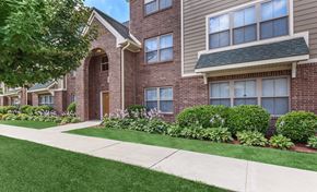 South Bend apartment for rent - A brick building with a green lawn in front.