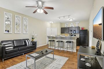 Edwardsville apartment for rent - A black leather couch sits in a living room with a glass coffee table in front of it.