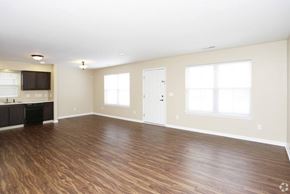 South Bend apartment for rent - A spacious room with wooden flooring and white walls.