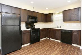 South Bend apartment for rent - A black refrigerator is in a kitchen with wooden cabinets.