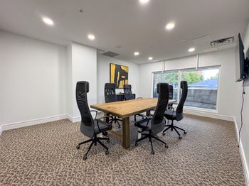 A conference room with a table, chairs, and a television.
