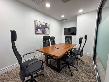 A conference room with a wooden table and black chairs.
