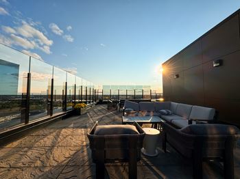 A rooftop patio with a couch, chairs, and a table with a view of the city.