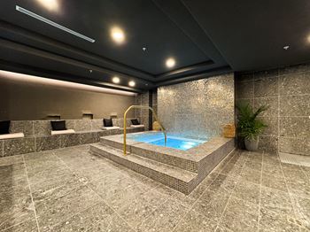 A small indoor swimming pool with a stone wall and floor.