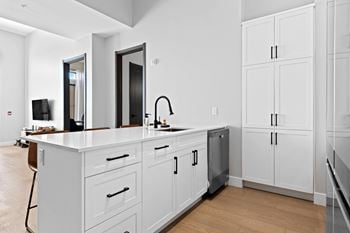 A modern kitchen with white cabinets and a wooden floor