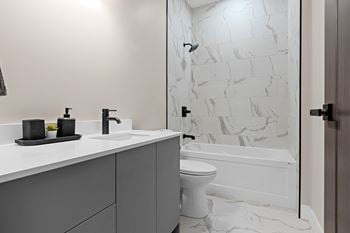 A white toilet sits in a bathroom with a marble wall
