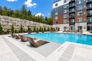 Kanata apartment for rent - A swimming pool with lounge chairs and a building in the background.