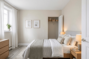 Kingston apartment for rent - A bedroom with a bed, nightstand, and a window with white curtains.