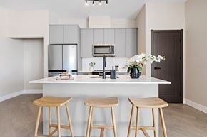 Kanata apartment for rent - A kitchen with a white counter and bar stools aat The Woods at 180 Kanata Avenue Apartments, Ontario, K2T 0T4