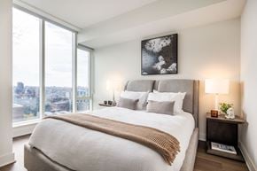 Ottawa apartment for rent - A bedroom with a large bed and a view of the city.