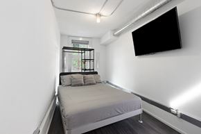 Ottawa apartment for rent - A bedroom with a bed, a window, and a flat screen TV mounted on the wall.