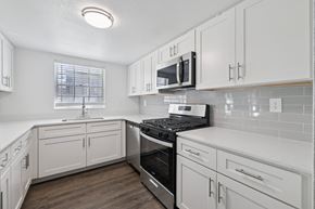 Tampa apartment for rent - A kitchen with white cabinets and a black stove top oven.