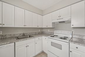 Tampa apartment for rent - A kitchen with white cabinets and a white stove top oven.