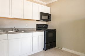 Sarasota apartment for rent - a kitchen with white cabinets and black appliances  at North Washington Apartments
