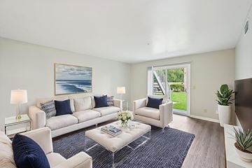 Jacksonville apartment for rent - A living room with a white couch, a coffee table, and a painting of a beach scene on the wall.