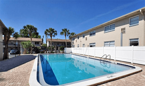 Lakeland apartment for rent - A swimming pool in front of a building with a white fence.