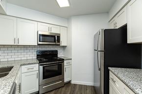 Tampa apartment for rent - A kitchen with white cabinets and black appliances.