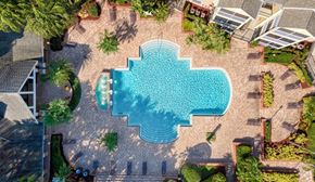 Casselberry apartment for rent - A swimming pool surrounded by a stone patio and landscaping.