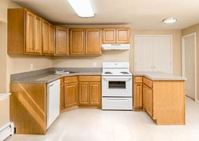 New Brunswick apartment for rent - a kitchen with white appliances and wooden cabinets at Raritan Crossing Apartment Homes, New Jersey
