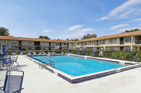 Eustis apartment for rent - A swimming pool surrounded by lounge chairs and umbrellas in front of a building.
