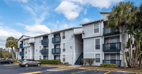 Tampa apartment for rent - an apartment building with a parking lot and palm trees at Sunscape Apartment Homes, Florida, 33613