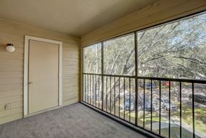 Tampa apartment for rent - A balcony with a view of a parking lot and trees.