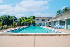 Tampa apartment for rent - A swimming pool in front of a building with a fence around it.