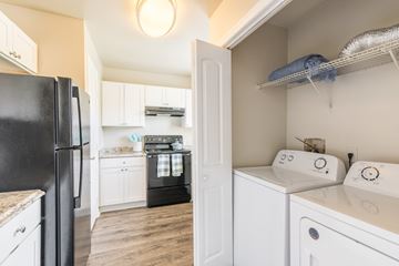 Orlando apartment for rent - A black refrigerator is in a kitchen with white cabinets.