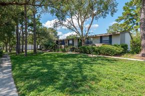 Eustis apartment for rent - A sunny day at a park with a walking path and a building in the background.