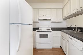 Tampa apartment for rent - A spacious kitchen with white round inset cabinets, dark contrasting counter tops, matching white stove, refrigerator, and dishwasher