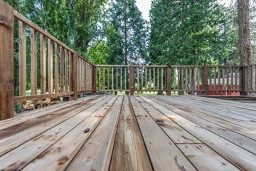Vancouver apartment for rent - A wooden deck with a railing and trees in the background.