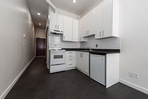 Vancouver apartment for rent - a kitchen with white cabinets and white appliances and black counter tops