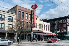 Vancouver apartment for rent - a view of a street corner with people walking and cars parked on the side of the road
