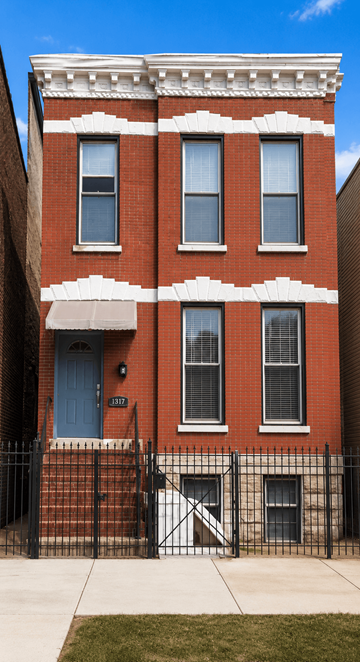 Chicago apartment for rent - A red brick building with a blue door and a black fence.