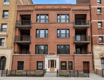 Chicago apartment for rent - A red brick building with a black fence in front.