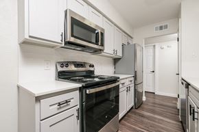 Richardson apartment for rent - A kitchen with white cabinets and a black stove top oven.