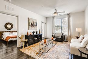 Orlando apartment for rent - Model living room with wood-designed flooring, ceiling fan, and patio door at EOS in Orlando, FL