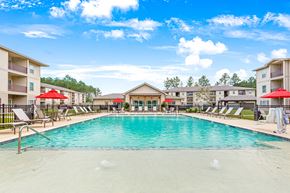 Covington apartment for rent - Resort-style swimming pool surrounded by lounge chairs and overlooking the clubhouse at Reagan Crossing in Covington, LA