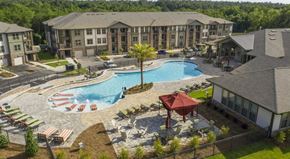 Fairhope apartment for rent - Overlooking the resort-style swimming pool at The Retreat at Fairhope Village in Fairhope, AL with poolside cabana, lounge chairs, tables and residential building in the distance