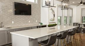 Fairhope apartment for rent - Communal kitchen with bar-style seating and large TV at The Retreat at Fairhope Village in Fairhope, AL