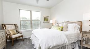Fairhope apartment for rent - Furnished master bedroom with ceiling fan, window and carpet flooring at The Retreat at Fairhope Village in Fairhope, AL