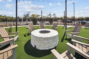 Cocoa apartment for rent - A white fire pit sits in the middle of a grassy area surrounded by wooden chairs. at Allegra at Cocoa in Cocoa, FL, 32926
