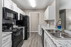 Fairhope apartment for rent - a kitchen with white cabinets and black appliances